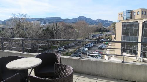 a balcony with chairs and a table and a view of a parking lot at Residence Services Calypso Calanques Plage in Marseille