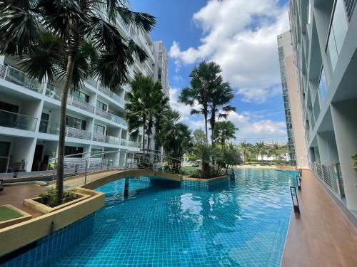 a swimming pool in the middle of a building with palm trees at Laguna Beach 1 Condo&Resort Pattaya Bey Aey in Jomtien Beach