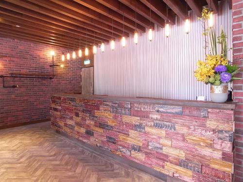 a lobby with a brick wall and a counter with flowers at City Suites - Kaohsiung Pier2 in Kaohsiung