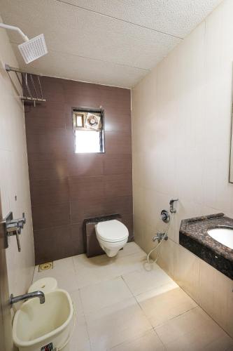 a bathroom with a toilet and a sink at Hotel New Apex in Ankleshwar