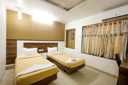 AnkleshwarHotel New Apex的有两张床和一扇窗户的房间