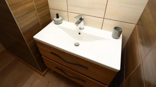 ein weißes Waschbecken im Bad mit Holzwänden in der Unterkunft Kokavská izba - Apartmány in Kokava na Rimavica