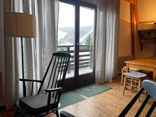 una camera con una sedia, un tavolo e una finestra di Chalet montagnard avec balcon, proche piste et centre - FR-1-814-77 a Besse-et-Saint-Anastaise