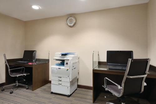 an office with two desks and a computer on a wall at Ramada Downtown Abu Dhabi in Abu Dhabi