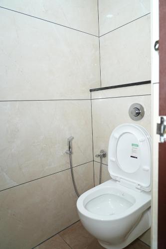 a white toilet in a bathroom with a shower at Hotel Kalyan Suites in Bengaluru