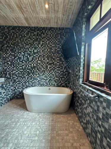 a bath tub in a tiled bathroom with a window at NIKARA Luxury Beach House in Tissamaharama