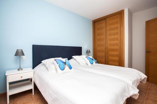 a bedroom with a white bed and a wooden door at Villa con Piscina ,Vista Mar y campo de golf in Caleta De Fuste