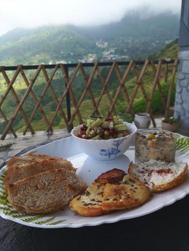 a plate of food with bread and a bowl of fruit at Paarli Dhara,Bir in Bīr