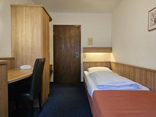 a small room with a bed and a desk at ARRIVEL Hotel am Bergson - bisher Hotel Neuner in Munich