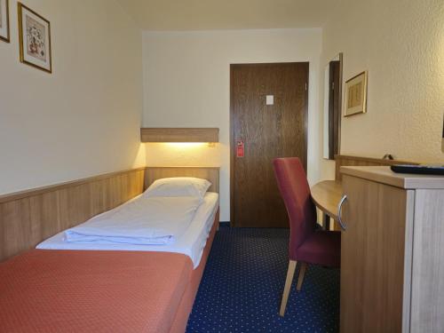 a bedroom with a bed and a desk and a chair at ARRIVEL Hotel am Bergson - bisher Hotel Neuner in Munich