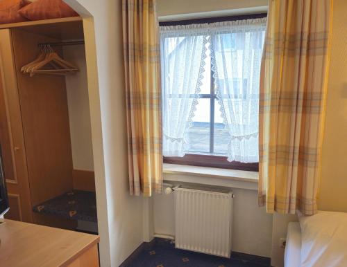 a bedroom with a window with curtains and a radiator at ARRIVEL Hotel am Bergson - bisher Hotel Neuner in Munich