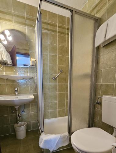 a bathroom with a shower and a toilet and a sink at ARRIVEL Hotel am Bergson - bisher Hotel Neuner in Munich