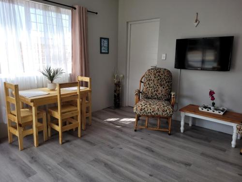 a living room with a table and a chair and a television at Heuning Nessie in Bredasdorp