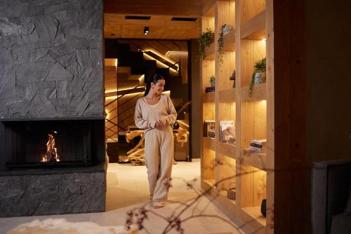 a woman standing in a room with a fireplace at Villa La Roca Garden and Spa in Kościelisko