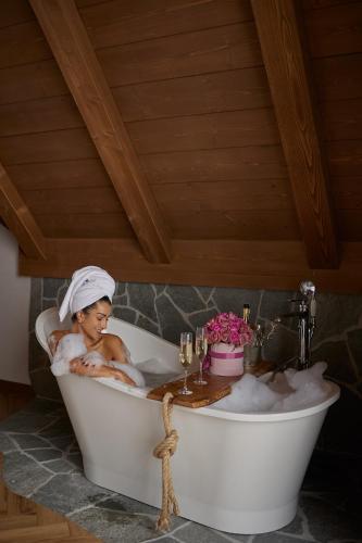 a woman sitting in a bath tub with a towel on her head at Villa La Roca Garden and Spa in Kościelisko
