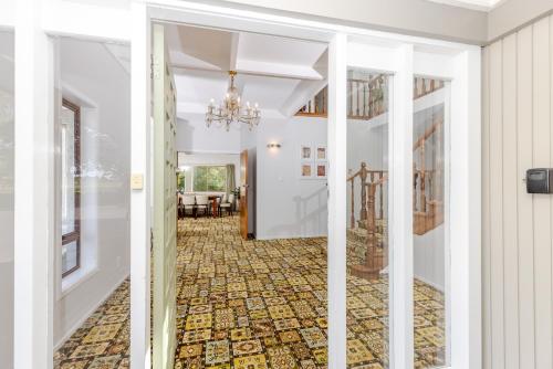 a hallway with white walls and a chandelier at Matangi Manor, 9 bedroom home in park-like grounds in Tamahere