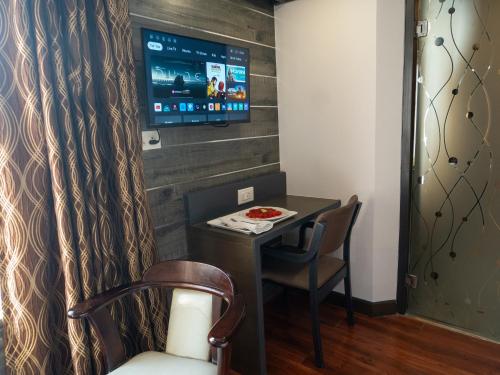a room with a table and a tv on a wall at Hotel Pravasa Stay in Vadodara
