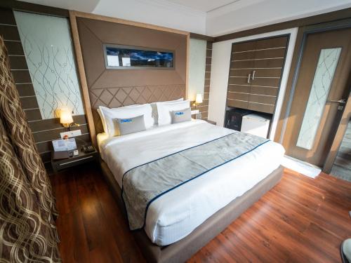 a bedroom with a large bed with white sheets and pillows at Hotel Pravasa Stay in Vadodara
