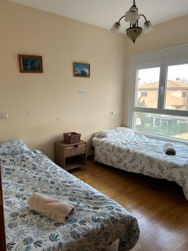 two beds in a room with a window at Casita Azul Homestay in Cáseda