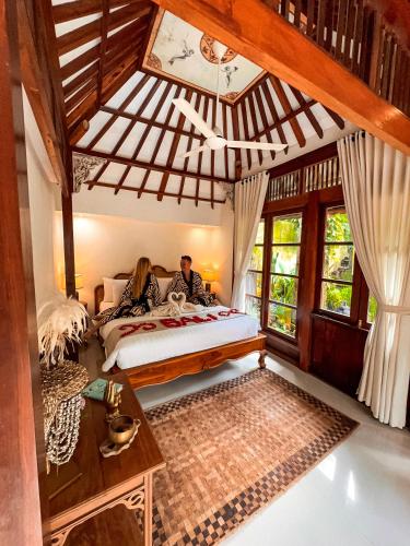 two people sitting on a bed in a room at Bali Maison in Ubud