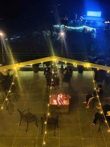 a group of people sitting on a patio at night at Hotel Chail Residency in Chail