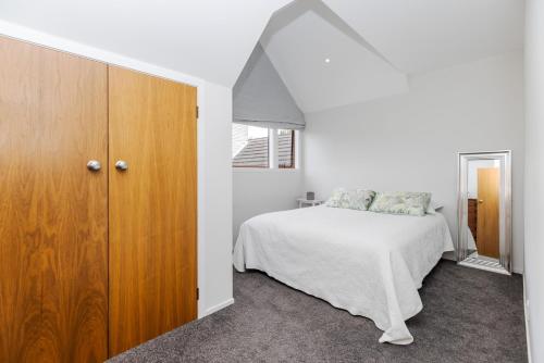 a bedroom with a bed and a wooden cabinet at Matangi Manor, 9 bedroom home in park-like grounds in Tamahere