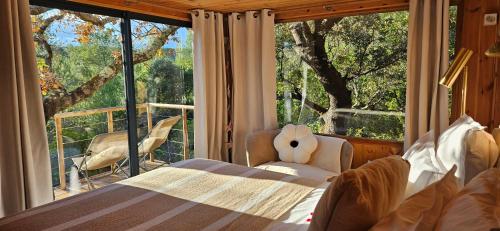 une chambre avec un lit et une grande fenêtre dans l'établissement Caban'AO, à Saint-Just-et-Vacquières