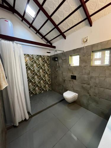a bathroom with a toilet and a stone wall at Birdsong Coffee Estate Stay in Madikeri