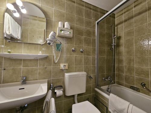 a bathroom with a toilet and a sink and a mirror at ARRIVEL Hotel am Bergson - bisher Hotel Neuner in Munich