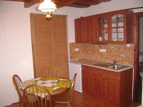 a kitchen with a table and a sink and a table and chairs at Pásztor Vendégház in Poroszló