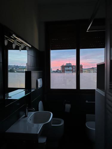 a bathroom with two sinks and a toilet and two windows at Oriani39 B&B in Bologna