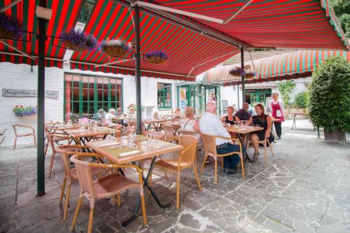 a group of people sitting at tables in a restaurant at Hotel Au Repos Des Chasseurs in Brussels