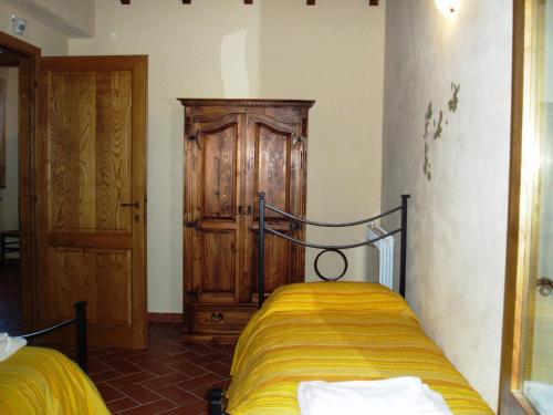 サトゥルニアにあるLa Casa Delle Cascateのベッドルーム1室(ベッド1台付)、木製キャビネットが備わります。