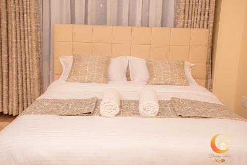 a large bed with white sheets and pillows at Dreamy Deluxe Furnished Apartment in Nakuru