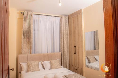 a bedroom with a mirror and a bed with pillows at Dreamy Deluxe Furnished Apartment in Nakuru