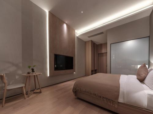 a bedroom with a large bed and a flat screen tv at Qingdao Wushe Yujianshanju Tangchi Seaview Hotel in Qingdao