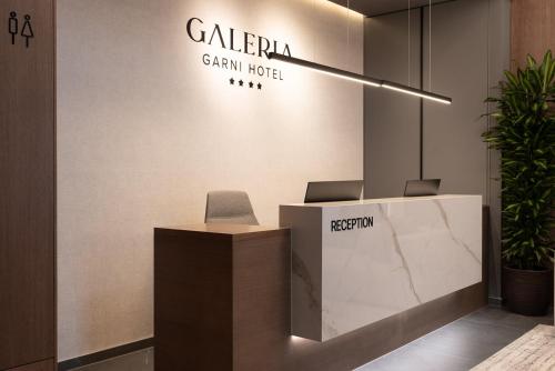 a reception desk in a lobby with a sign at Garni Hotel Galeria in Banja Luka