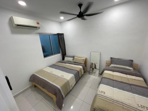 two beds in a room with a ceiling fan at Tun Aminah 14paxs near Nirvana Skudai in Skudai