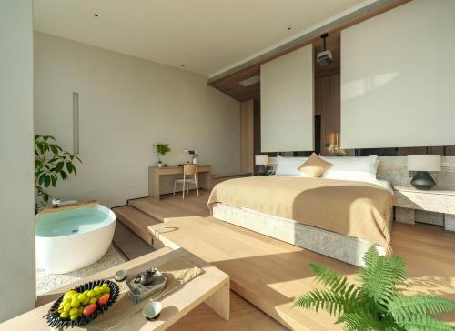 a bedroom with a bed and a tub in a room at Qingdao Wushe Yujianshanju Tangchi Seaview Hotel in Qingdao
