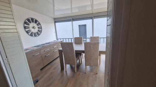 une salle à manger avec une table, des chaises et une horloge dans l'établissement Appartement en bord de plage - à 50 m de la mer, à Canet