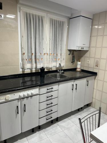 une cuisine avec des armoires blanches, un évier et une fenêtre dans l'établissement MAGIC II a 30 segundos de la Plaza Mayor y 1 minuto de la Catedral, à León