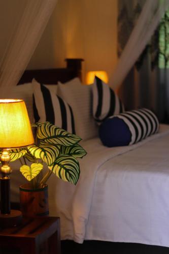 a bedroom with a bed with pillows and a lamp at Rawana Mount View - Ella in Bandarawela
