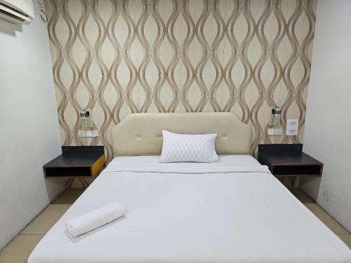 a bedroom with a white bed with two end tables at Hotel Twelve at 12 Kuantan Centre in Kuantan