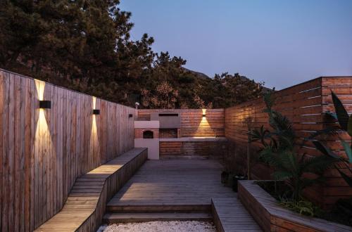 a wooden walkway next to a brick fence at Qingdao Wushe Yujianshanju Tangchi Seaview Hotel in Qingdao