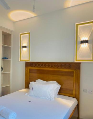 a bedroom with a white bed with two pictures on the wall at Habibi Homes in Mombasa