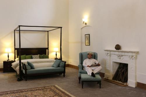 a man sitting in a room with a bed and a fireplace at Swat Serena Hotel in Saidu