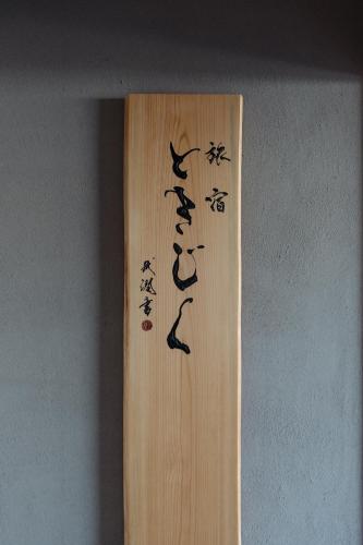 a wooden sign with asian writing on a wall at 旅宿ときじくTokijiku in Nachikatsuura