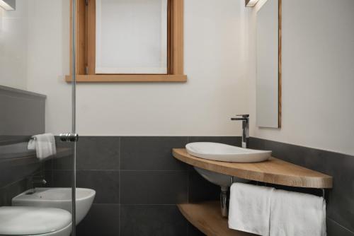 a bathroom with a sink and a toilet and a mirror at Alpen Hotel Chalet in Valdidentro