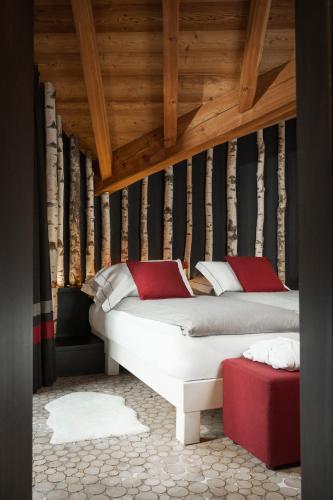a bedroom with two beds and a wooden ceiling at Alpen Hotel Chalet in Valdidentro