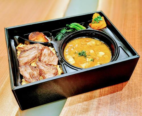 a box of food with meat and a bowl of soup at ひがし茶屋街らしく金沢 Hotel Rashiku kanazawa in Kanazawa